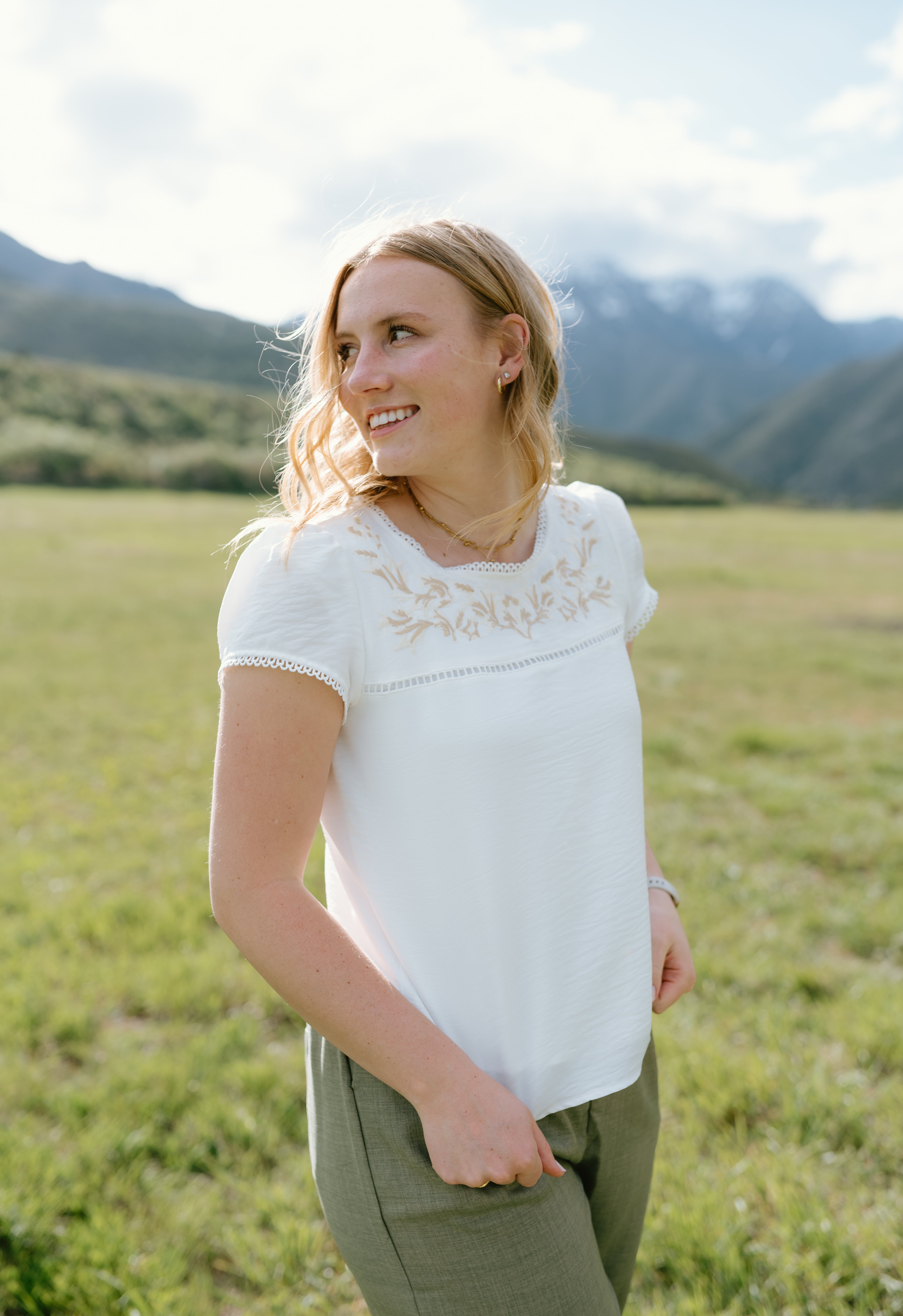 Relaxed Hampton Top with embroidery, worn outdoors in a scenic mountain setting, showcasing casual elegance.