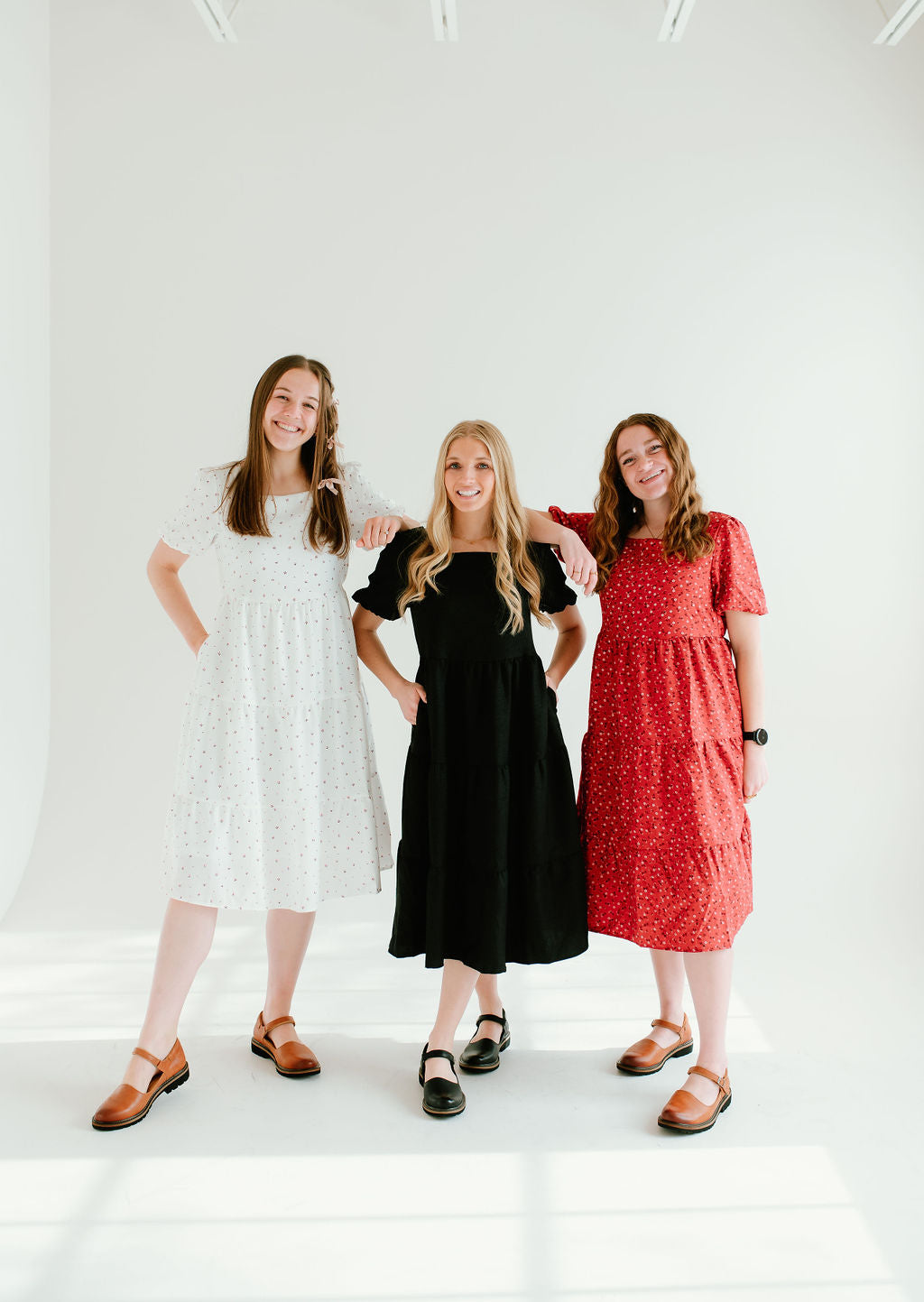 White floral, black, and red floral dresses with short sleeves and pockets.