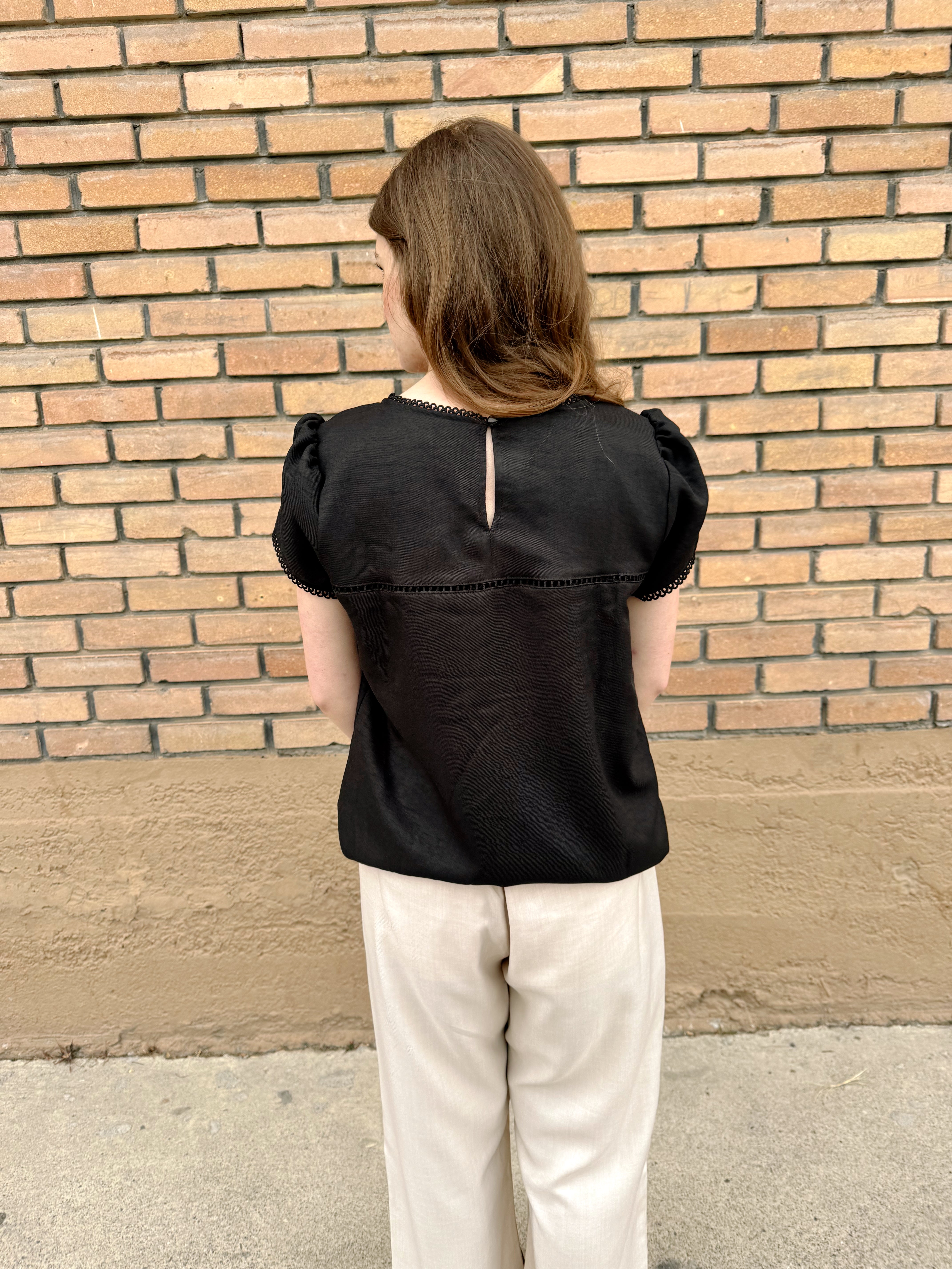 Black Hampton Top with puff sleeves and lace trim, showcased by Store Name.